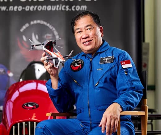 Dr Neo Kok Beng in a blue flight suit, holding a model aircraft